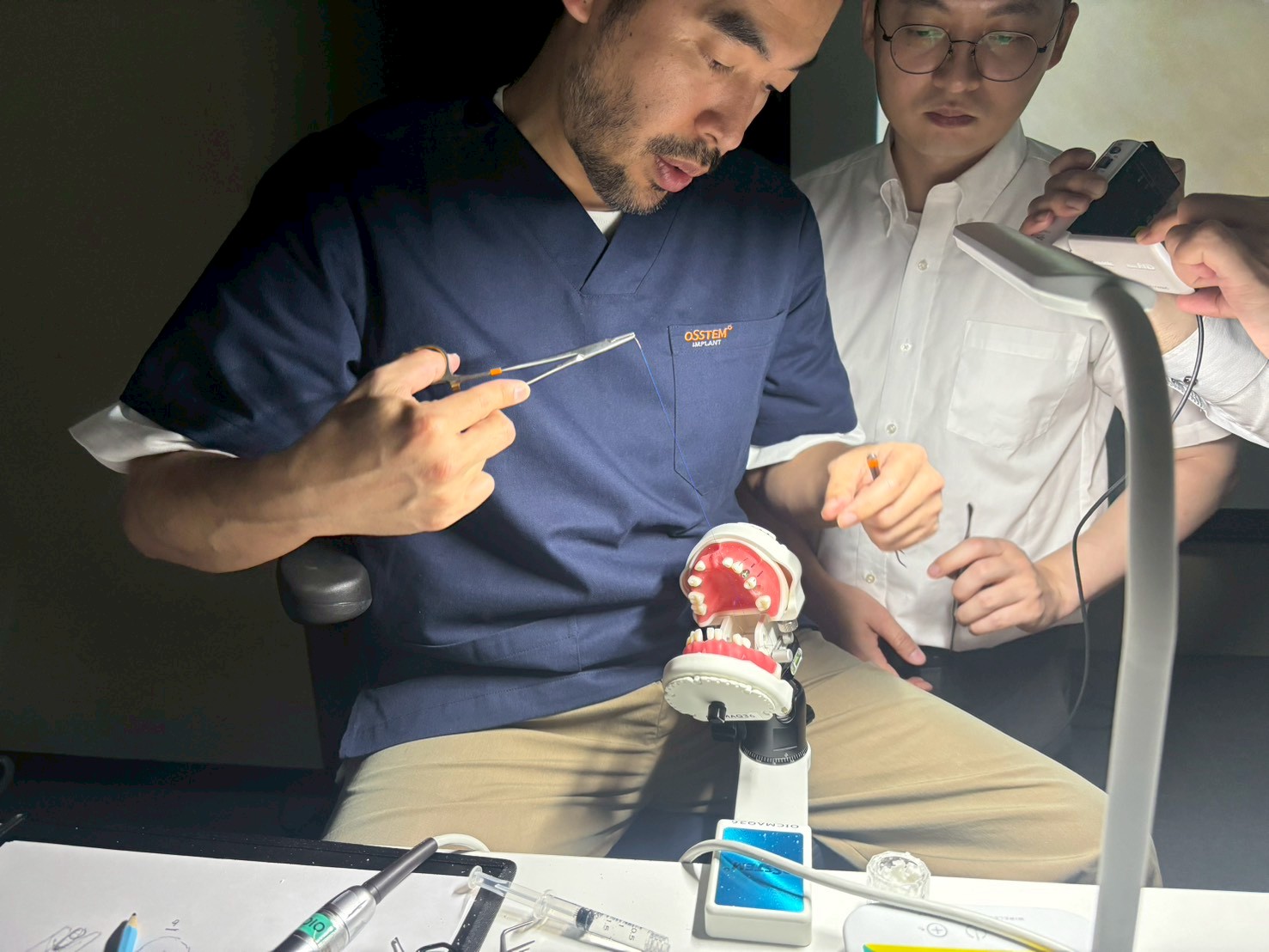 OSSTEM MASTER COURSEで顎模型を使い受講者にインプラント治療のポイントを説明する橋口隼人